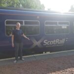 Standing in front of a blue train with the logo of ScotRail