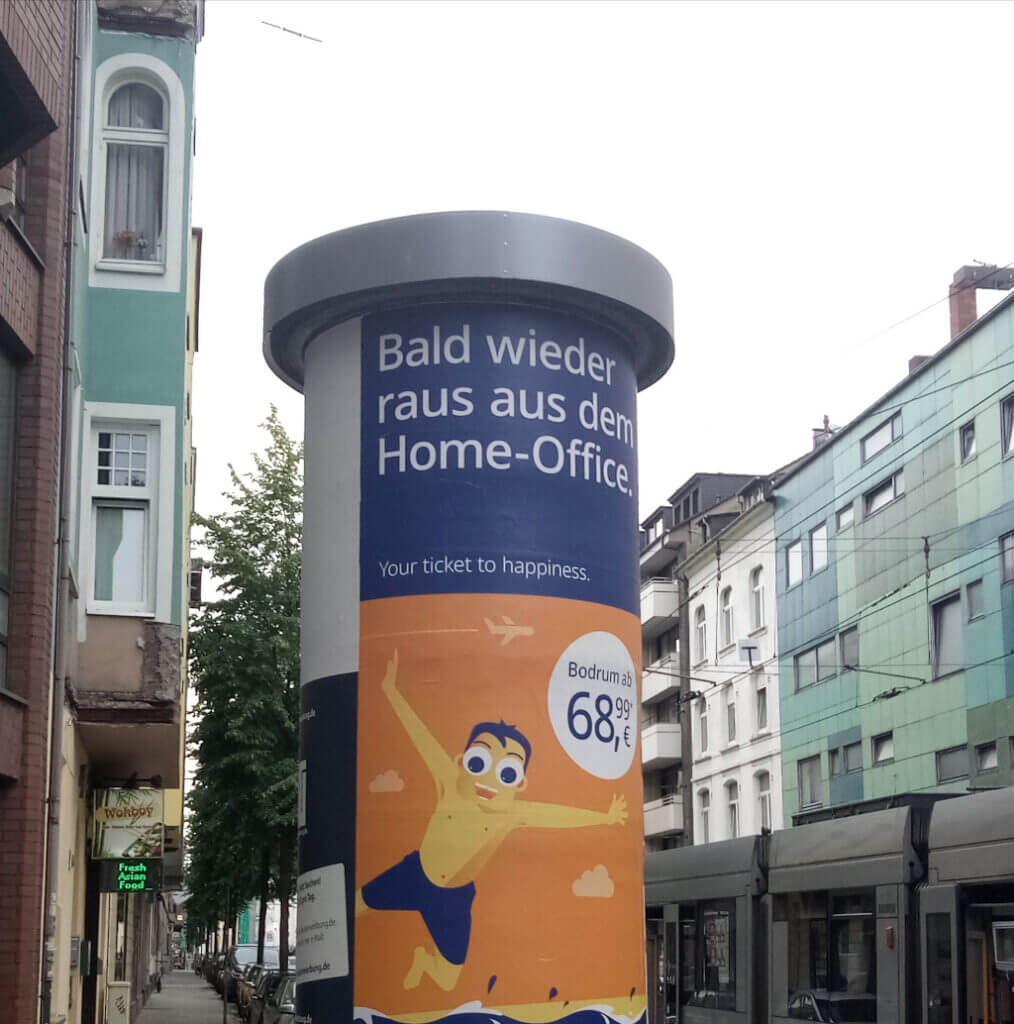 "Bald wieder raus aus dem Home-Office" Schriftzug auf einer Litfasssäule