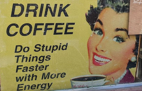 Sign showing a smiling women with a cup of black coffee and the text: Coffee - do stupid things faster with more energy