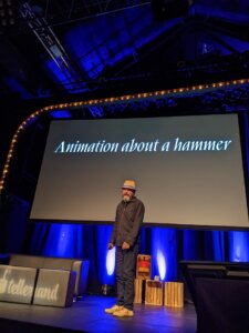 beardy man wearing a hat in front of a screen with the words Animation about a hammer