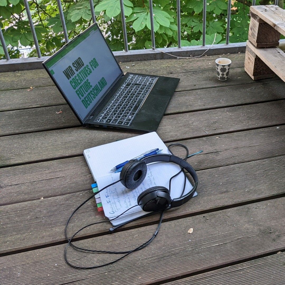 laptop, notebook and headphones on wooden balcony planks, laptop screen shows website of creatives for future deutschland