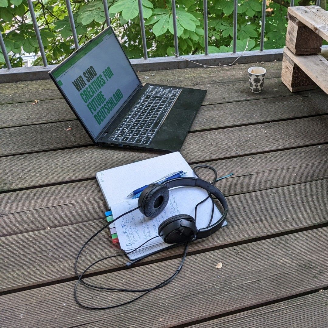 laptop, notebook and headphones on wooden balcony planks, laptop screen shows website of creatives for future deutschland