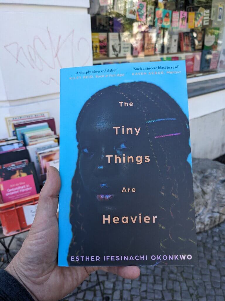 Book cover in front of a local book store: The Tiny Things are Heavier by Esther Okonkwo