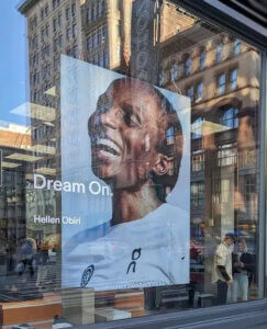 Portrait of athlete Hellen Obiri with the slogan Dream On in a shop window with reflections from the skyline opposite the street